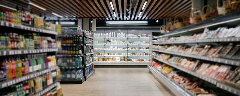 Shopping Along Shelves in Modern Supermarket Aisle Supermarket aisle with various products displayed on well-organized shelves, creating inviting atmosphere for customers while under modern lighting fixtures