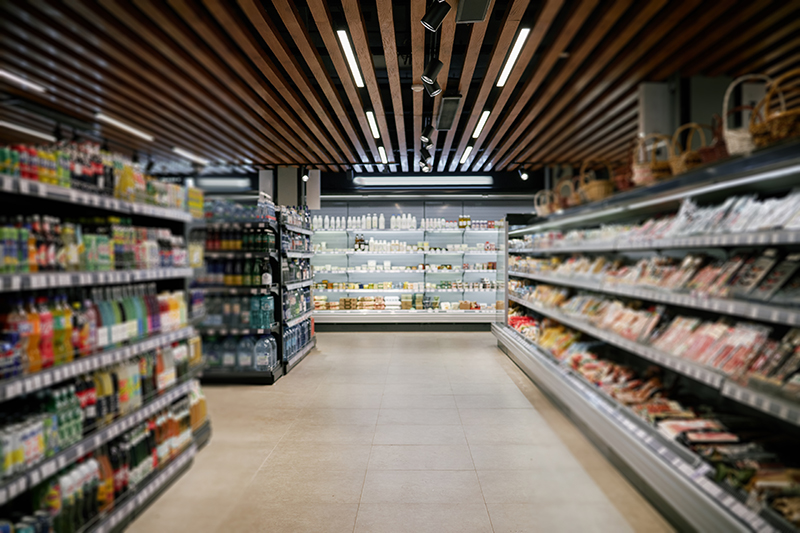Supermarket aisle with various products displayed on well-organized shelves, creating inviting atmosphere for customers while under modern lighting fixtures